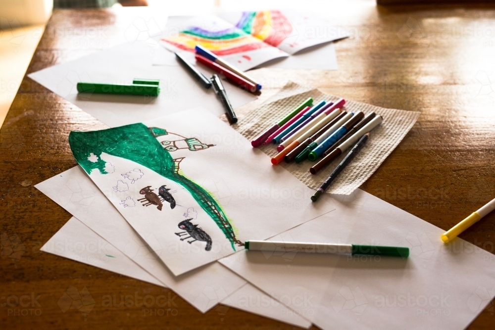 Child's drawing of sheep, dogs and a farm sitting on a table with textas - Australian Stock Image