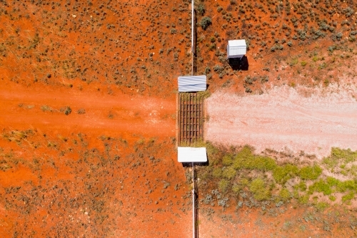 Aerial view of a mailbox and cattle grate in a dirt track across red barren land