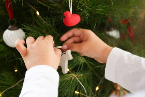 Close up of little hands decorating Christmas tree