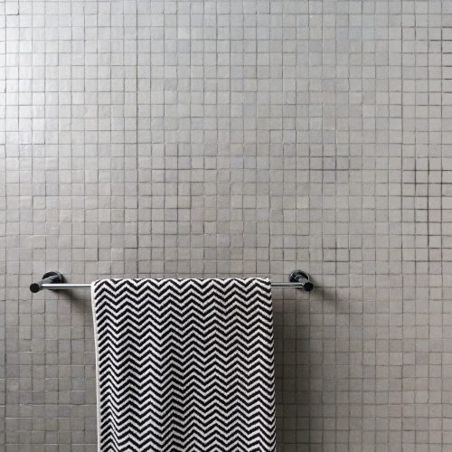 Background of mosaic square wall tiles with chevron towel on chrome towel rail