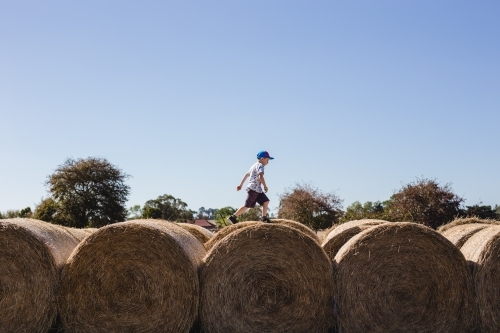 Boy running over the top of hay bales