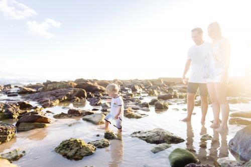 Boy walking through rockpool while parents watch on