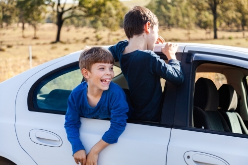 Boys climbing out of car window while waiting