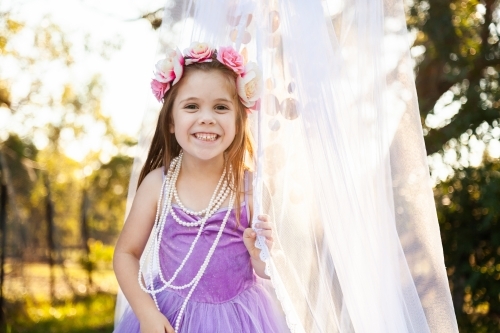 Child playing dress ups as princess with pearl necklace