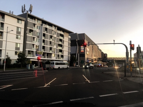 city intersection at dusk with busy asphalt road, tall buildings and cars