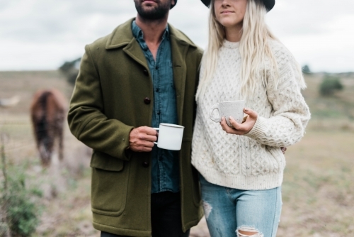 Close up of couple holding cups of coffee outside on farm