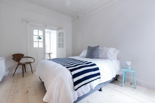 Crisp white Danish stylish bedroom with striped throw rug and blue side table