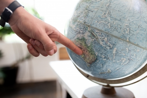 Finger pointing to map of Australia on round world globe