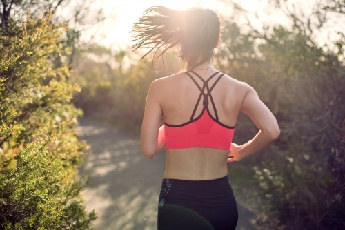 Fit Asian woman running for morning exercise, with lens flare