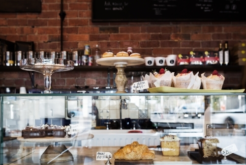 Horizontal cake display case in cafe with rustic wall behind