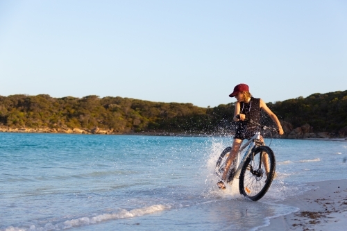 Kid riding bike through water on beach