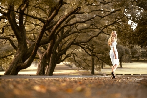 Lady walking amongst the trees in a white dress during autumn