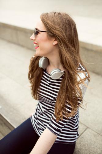 Laughing young woman looking away over shoulder with headphones