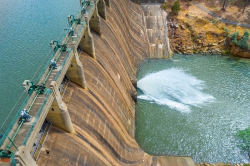 Looking down on a jet of water squirting from the bottom of a dam wall of a reservoir
