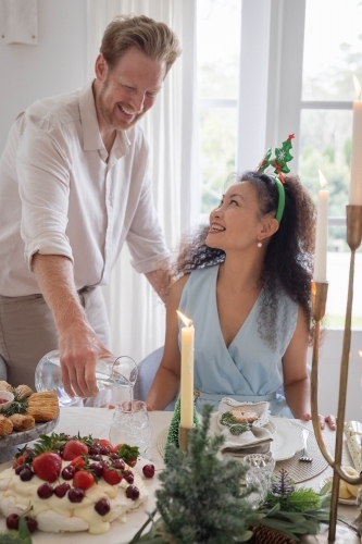 Man pouring water for his wife at Christmas table