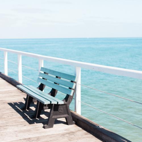 Park bench on a jetty overlooking ocean