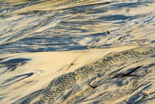 Patterns in wet yellow and black mineral sands on a beach at low tide