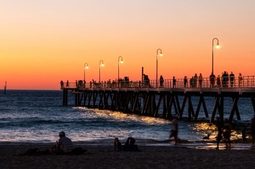 people on beach and jetty at sunset