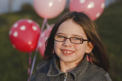 Smiling young girl with a bunch of pink balloons