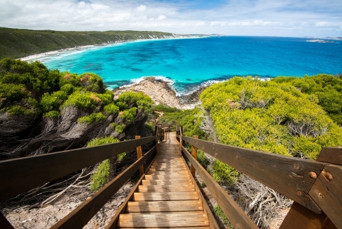 Steps leading down to rocks and colourful ocean  with sweeping views of coastline