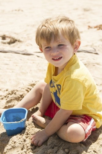 Toddler boy playing with sand at the beach
