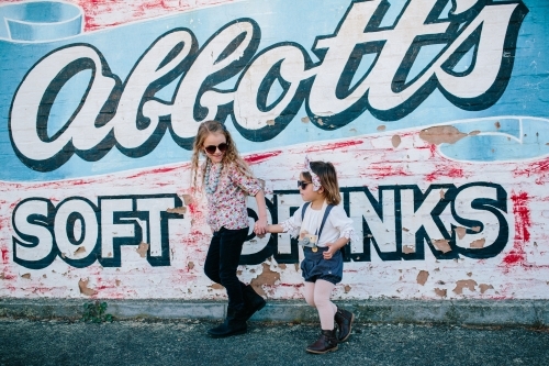 Two young fashionable urban kids with sunglasses and painted wall
