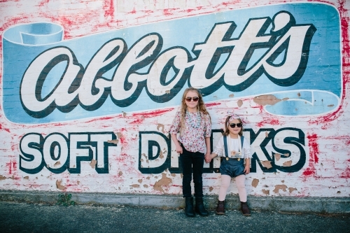 Two young fashionable urban kids with sunglasses and painted wall