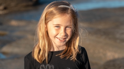 Under 10 girl smiling at camera at sunrise on beach