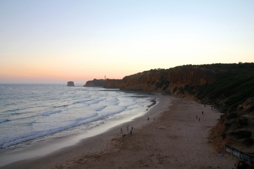 View along beach towards lighthouse at dusk