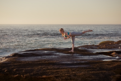 Woman doing yoga by the ocean