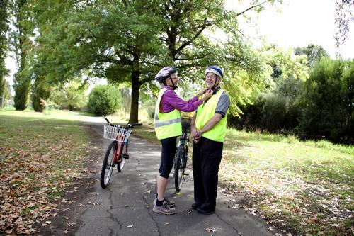 Woman helping disabled man with cycling helmet