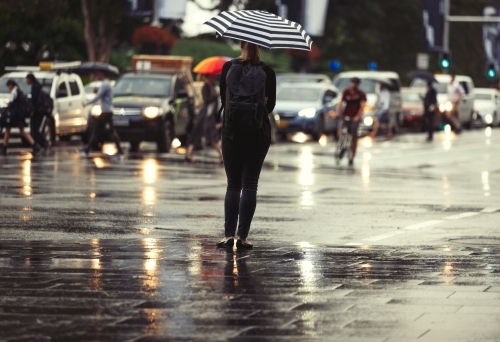 Woman standing in rain with striped umbrella