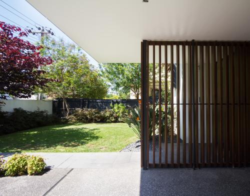 Wood screen detail of contemporary home front entrance and garden