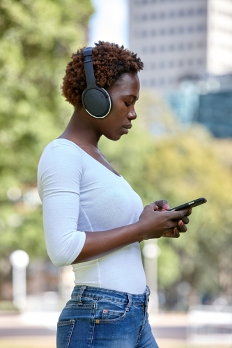 Young African woman listening to songs on mobile phone