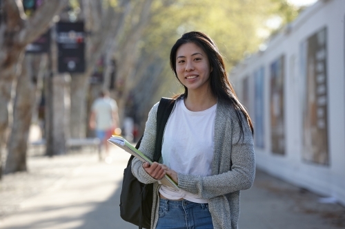 Young Asian female university student carrying study notes