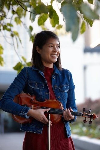 Young Asian female violin player practising outdoors