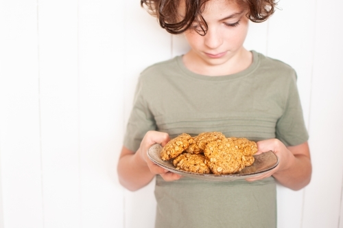 Young boy looking down at plate of cookies he is holding