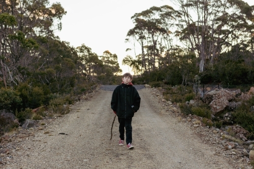 Young boy with stick on walking path