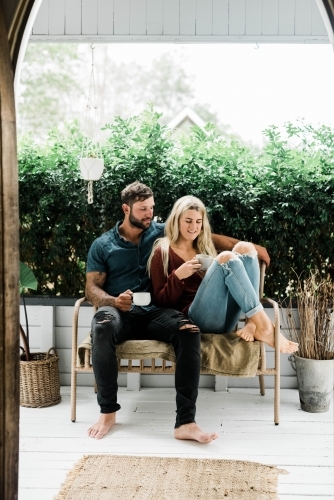Young couple sitting outside drinking coffee on verandah