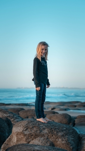 Young girl standing on rock at the beach