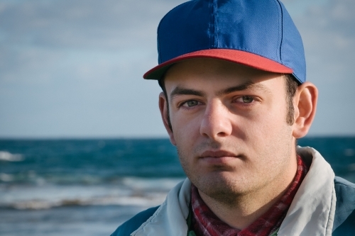 Young man wearing a cap at the ocean