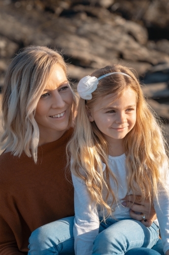 Young mother and daughter looking off camera at sunrise