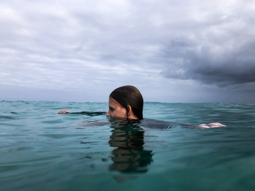 Young woman swimming in ocean on overcast day
