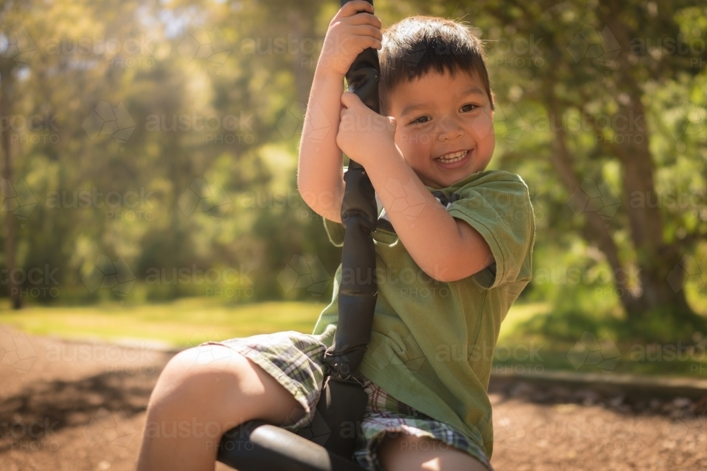 4 year old mixed race boy plays on a flying fox - Australian Stock Image