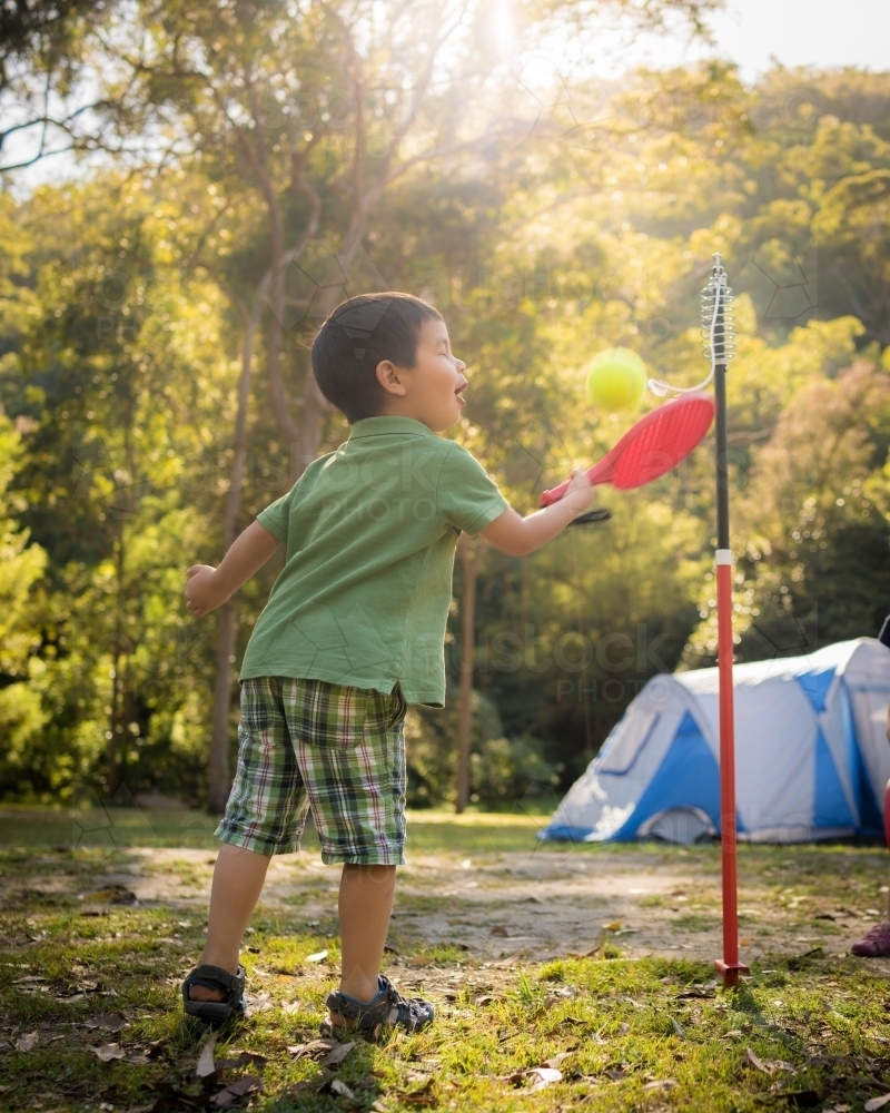 4 year old mixed race boy plays totem tennis on a camping trip - Australian Stock Image