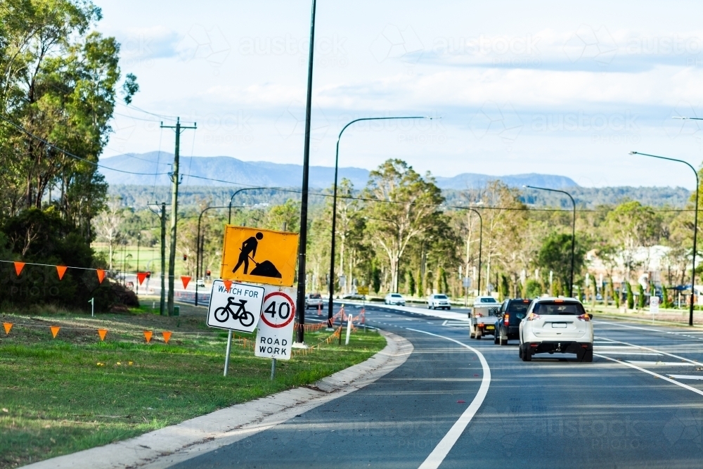 40 road work sign beside newly built road with cars traveling on it - Australian Stock Image