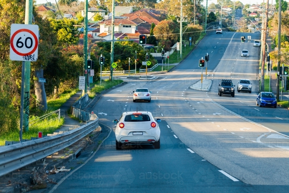 60 speed sign and cars driving down double lane road with turning lanes and traffic lights - Australian Stock Image