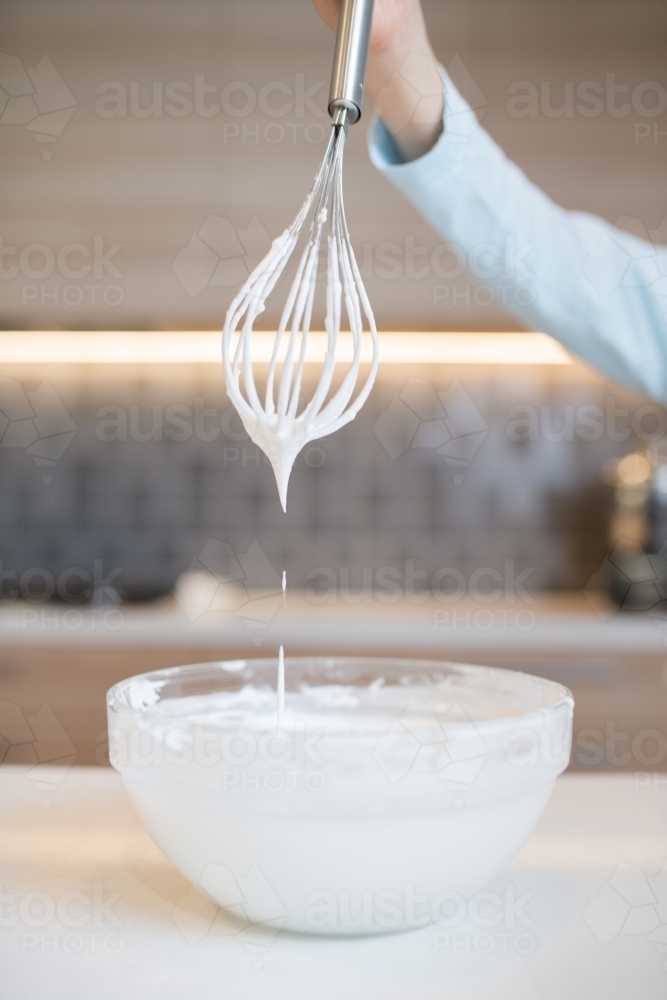 7 year old mixed race boy cooks at home with a whisk and bowl - Australian Stock Image