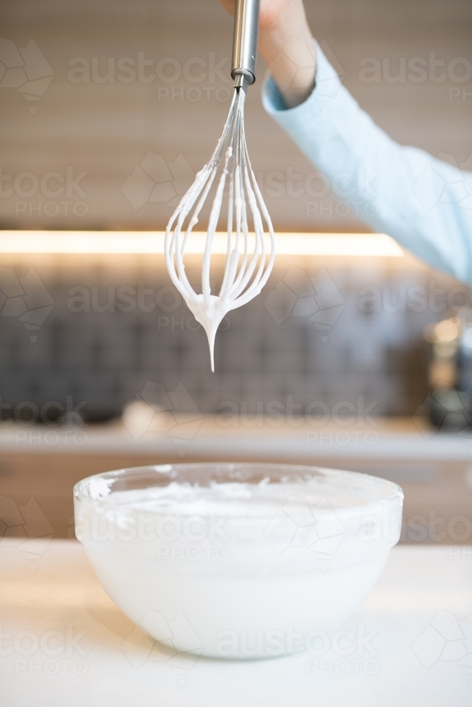 7 year old mixed race boy cooks at home with a whisk and bowl - Australian Stock Image