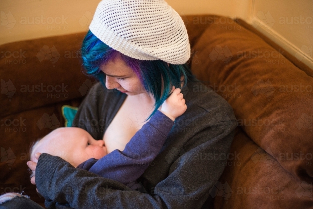 Mother looking down at child breastfeeding while child plays with hair - Australian Stock Image